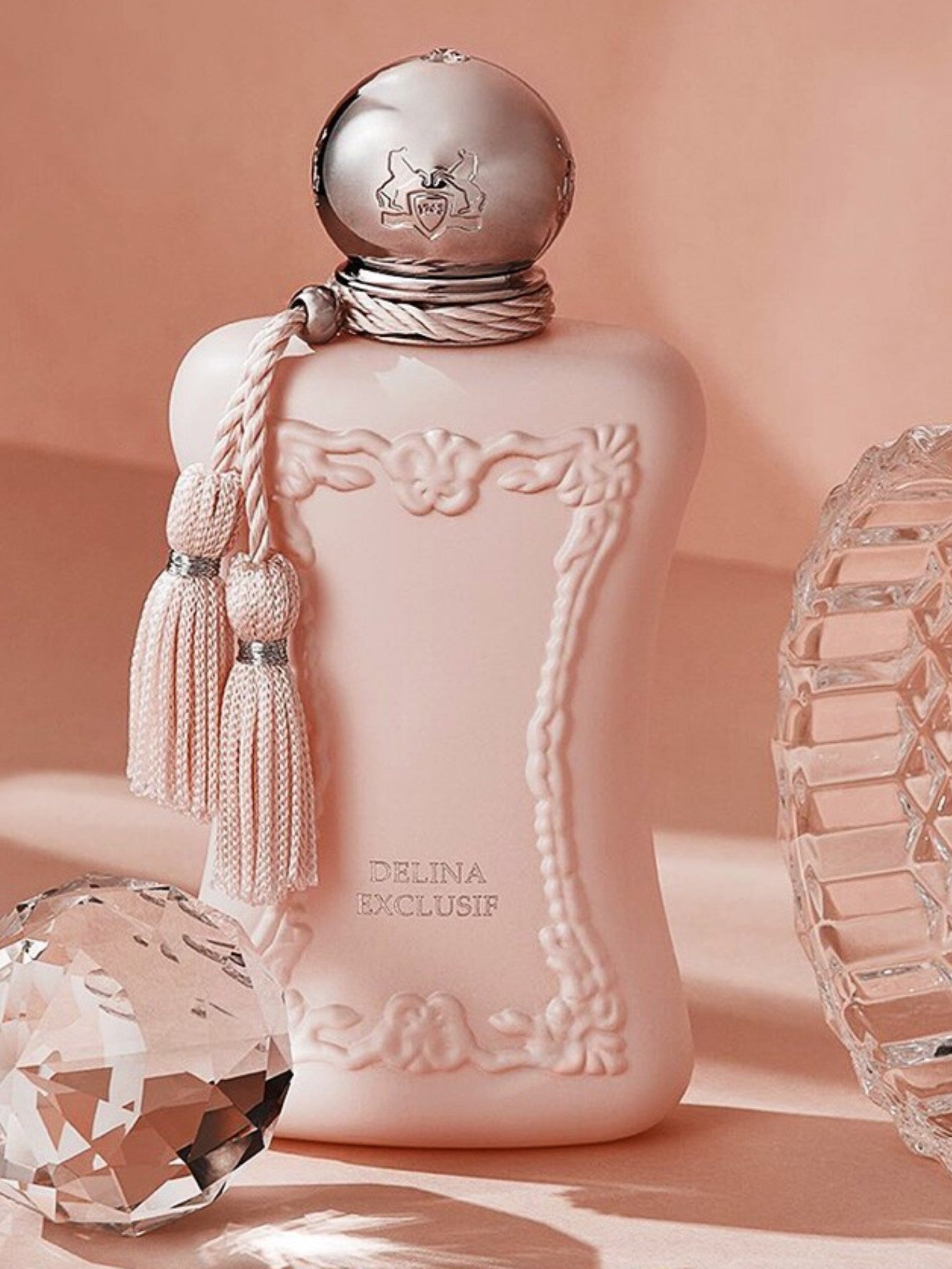 Pink perfume bottle with decorative elements on a soft pink background. Parfums De Marly, Monza Outlet, Monza Fashion, Shein Outlet
