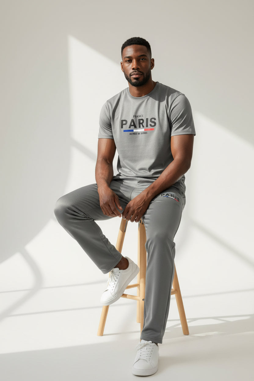 Man sitting on a stool wearing a gray t-shirt with branding and gray pants in a bright room. Antler, Monza Outlet, Monza Fashion, Shein Outlet