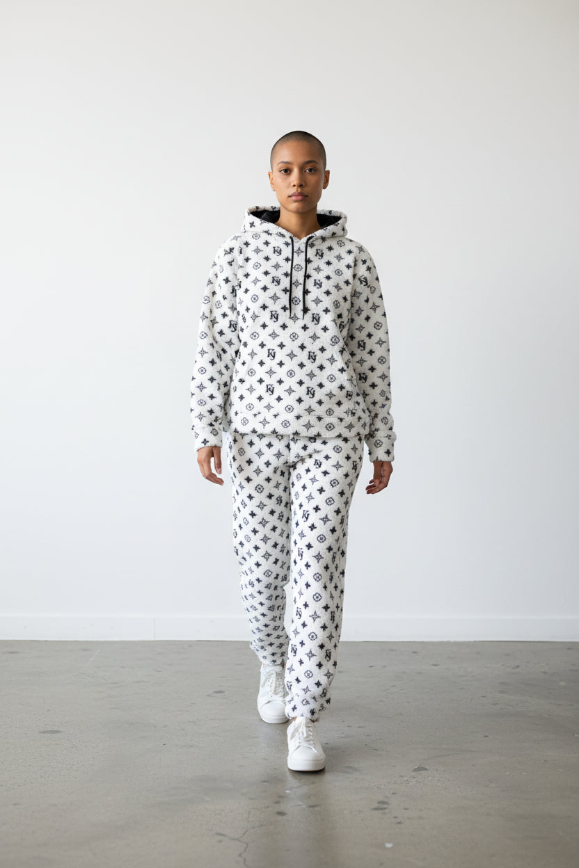 Person wearing a white hoodie and pants with black patterns on a plain background. Antler, Monza Outlet, Monza Fashion, Shein Outlet