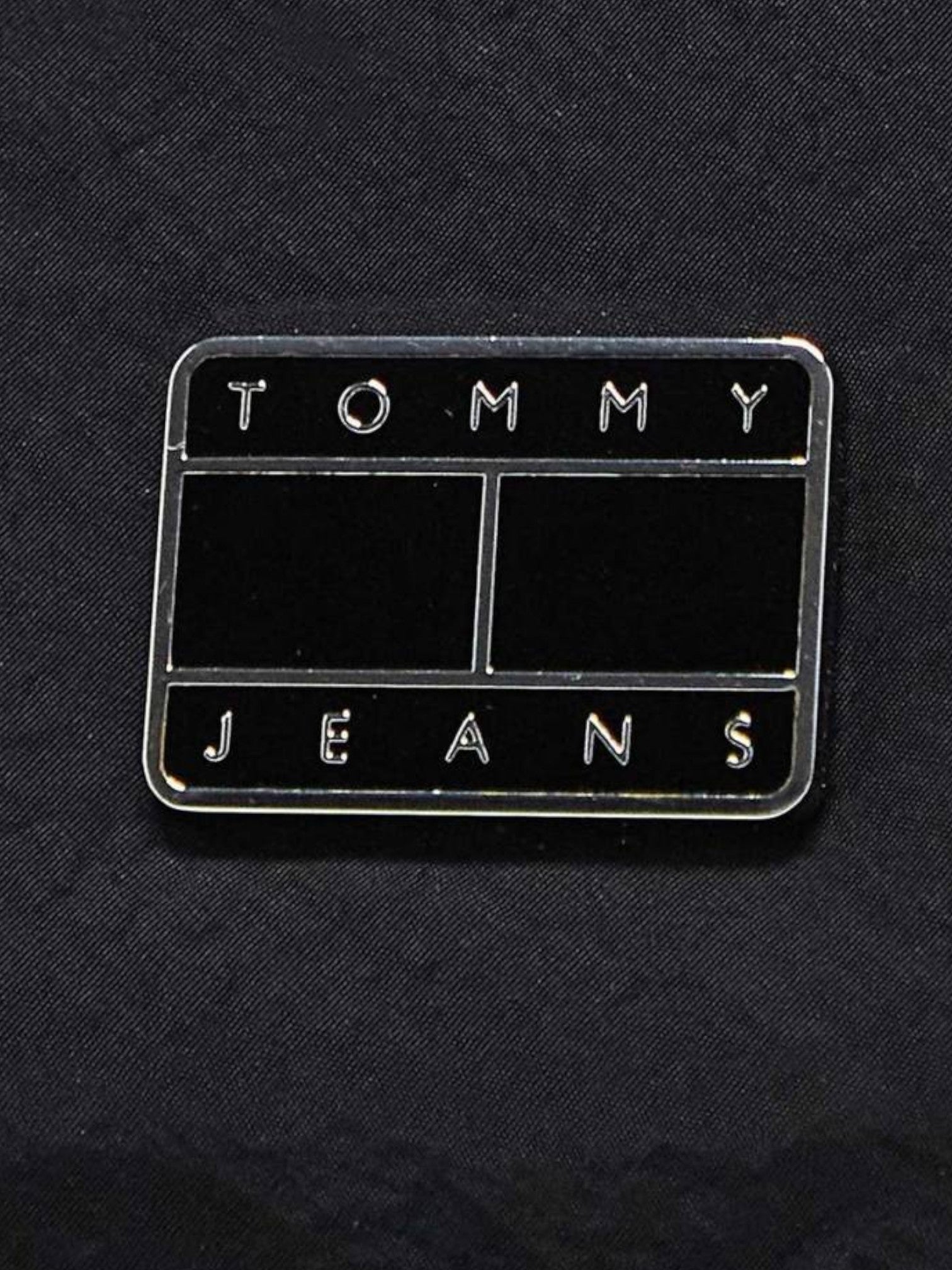 Tommy Jeans label on a black background. Tommy Jeans, Monza Outlet, Monza Fashion, Shein Outlet