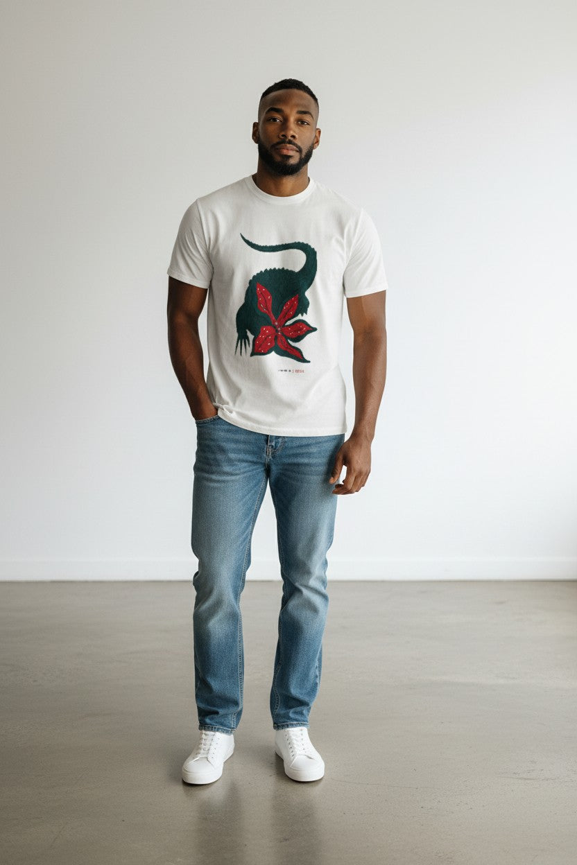 Man wearing a white t-shirt with a graphic design and blue jeans standing against a plain background. Lacoste, Monza Outlet, Monza Fashion, Shein Outlet