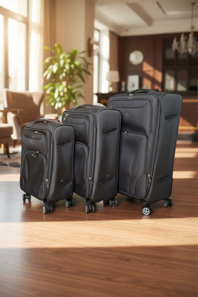 Three black suitcases of different sizes on a wooden floor in a room with a plant and furniture. Monza Outlet, Monza Fashion, Shein Outlet