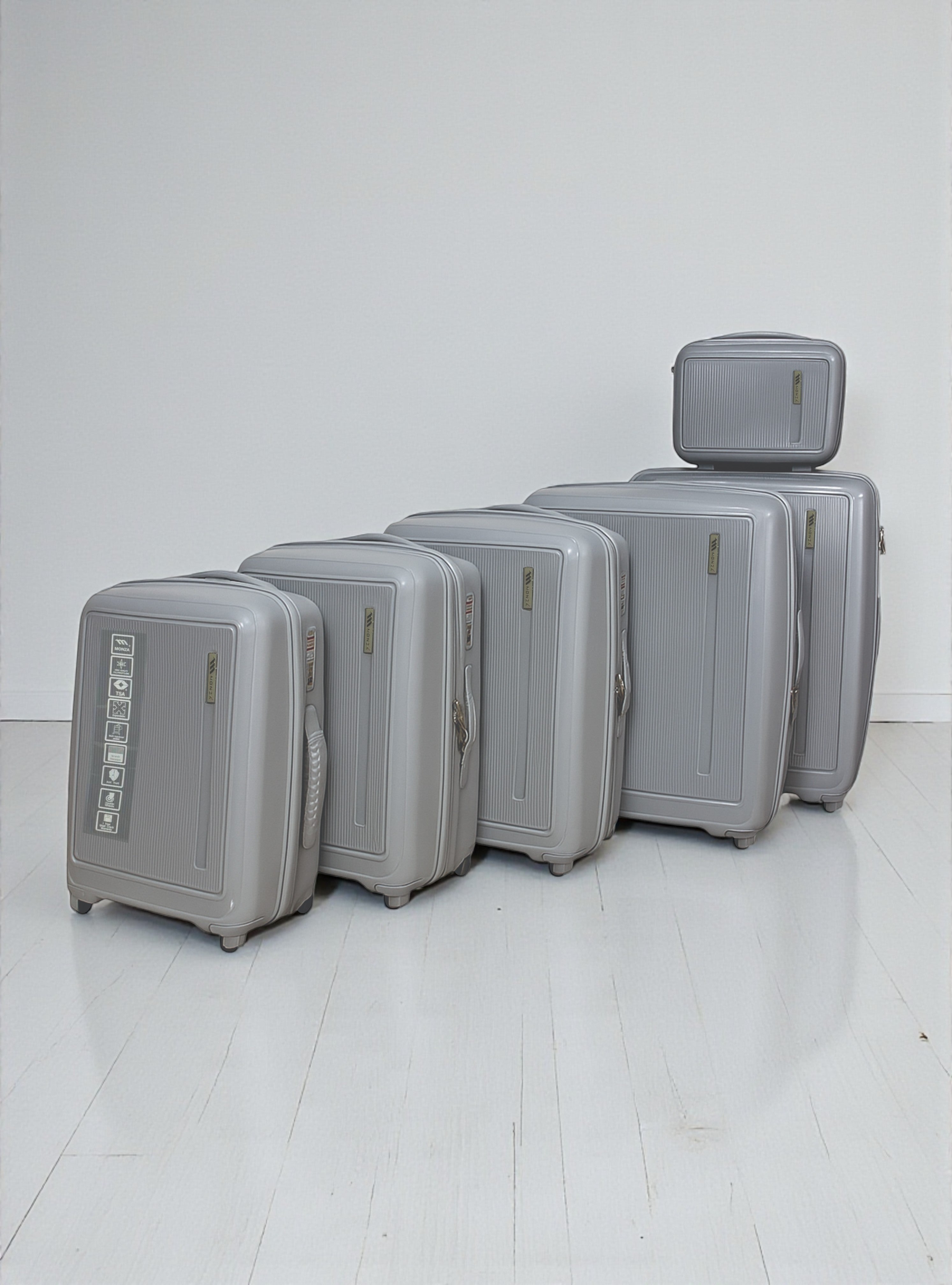 Set of gray suitcases of different sizes on a white floor. Monza Outlet, Monza Fashion, Shein Outlet