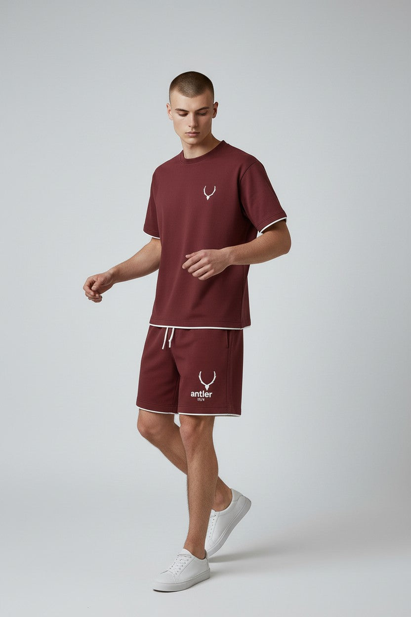 Man wearing a maroon t-shirt and shorts set with a logo on a light gray background. Antler, Monza Outlet, Monza Fashion, Shein Outlet
