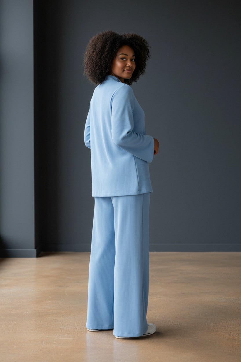 Person wearing a light blue suit standing against a dark gray wall. Antler, Monza Outlet, Monza Fashion, Shein Outlet