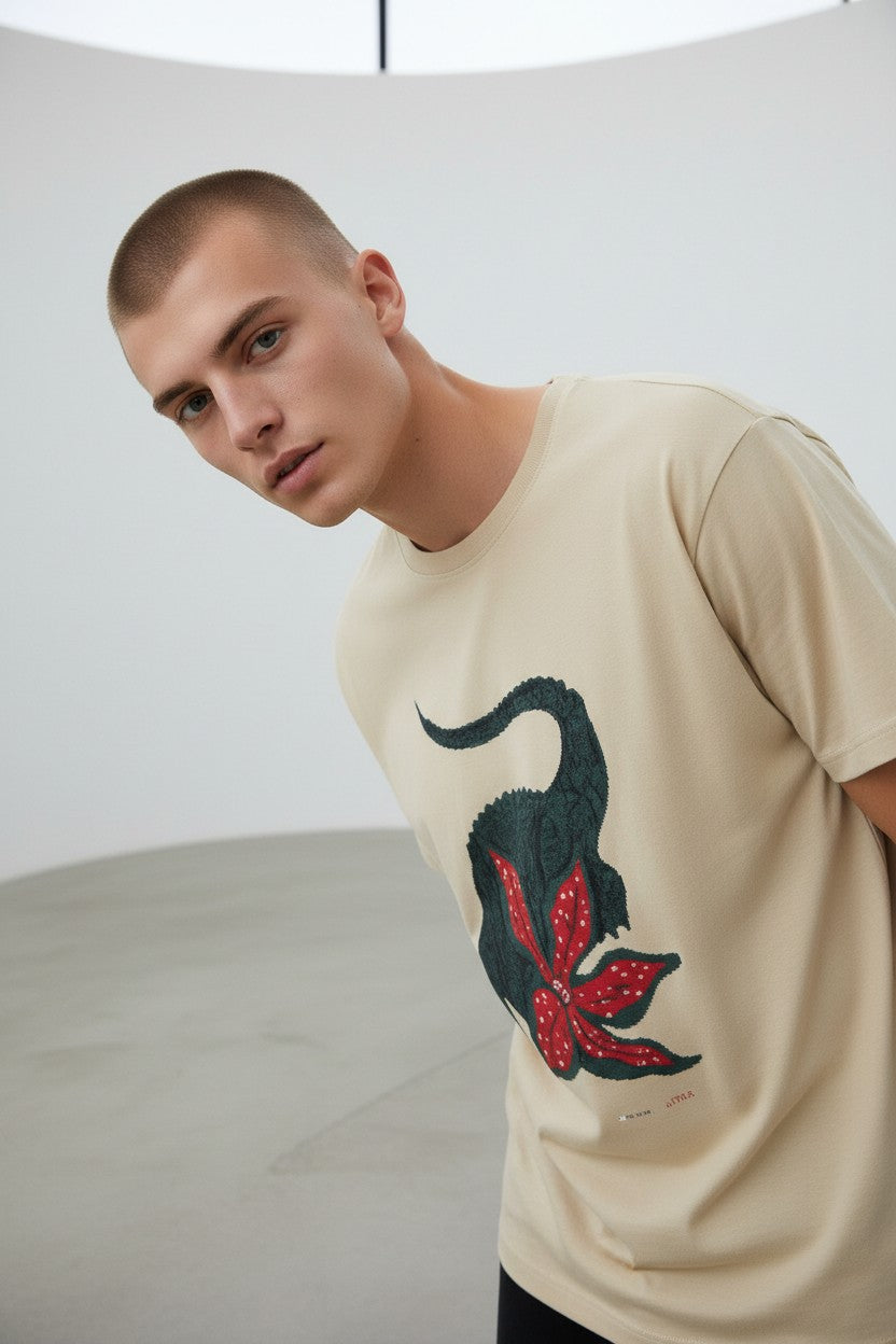 Man wearing a beige t-shirt with a black cat and red bow design on a plain background. Lacoste, Monza Outlet, Monza Fashion, Shein Outlet