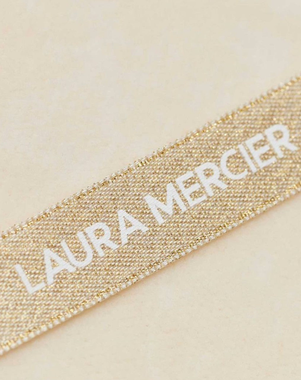 Gold ribbon with Laura Mercier text on a beige background  Laura Mercier Monza Outlet