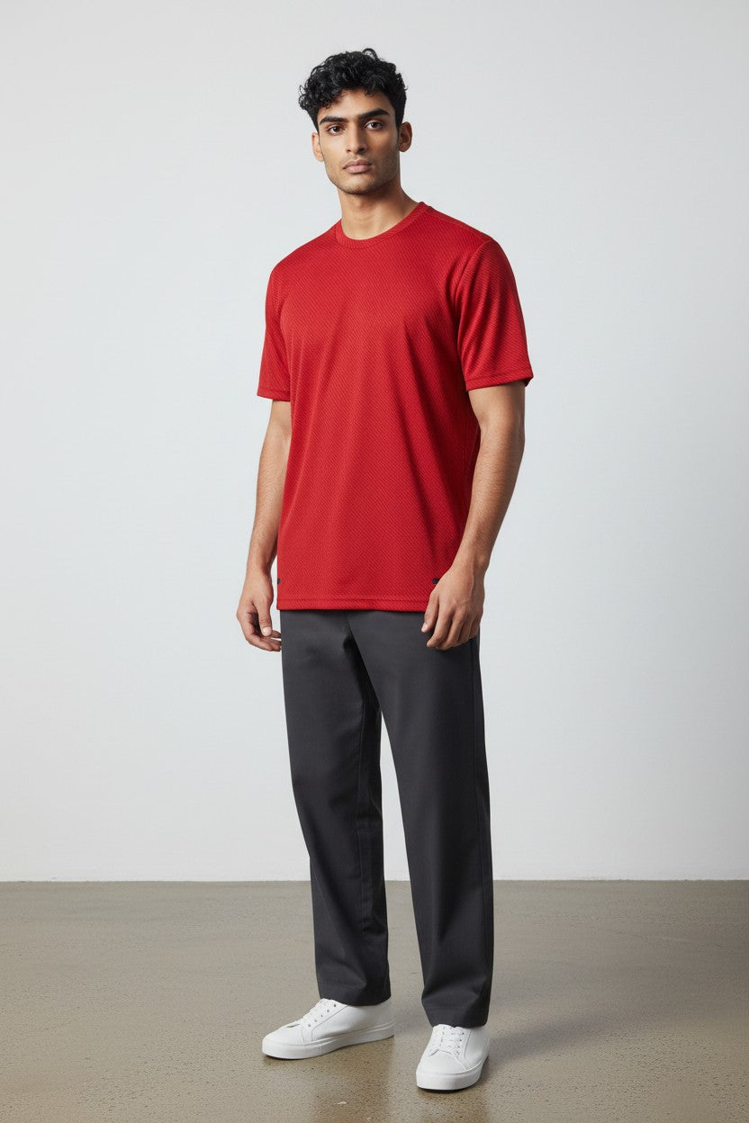 Man wearing a red t-shirt and gray pants standing against a white background. Adidas, Monza Outlet, Monza Fashion, Shein Outlet