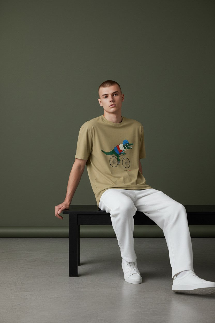 Man sitting on a bench wearing a beige t-shirt with a graphic design and white pants. Lacoste, Monza Outlet, Monza Fashion, Shein Outlet