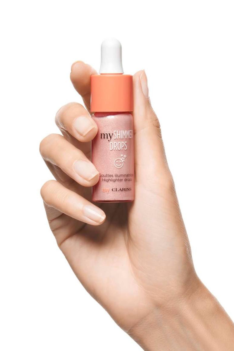 Hand holding a bottle of Clarins product on a white background monza outlet, Shein outlet, monza fashion