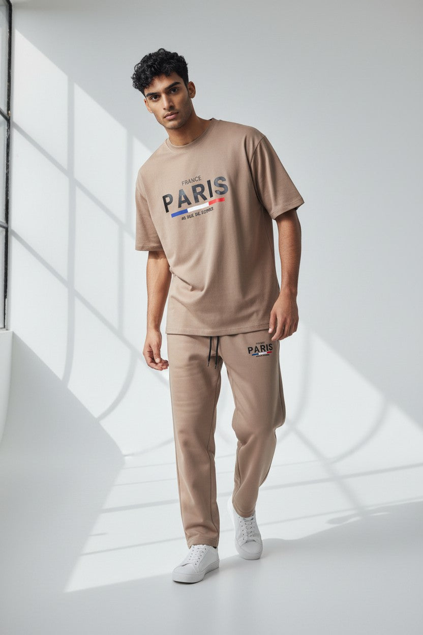 Man wearing a beige Paris t-shirt and pants in a minimalistic setting. Antler, Monza Outlet, Monza Fashion, Shein Outlet