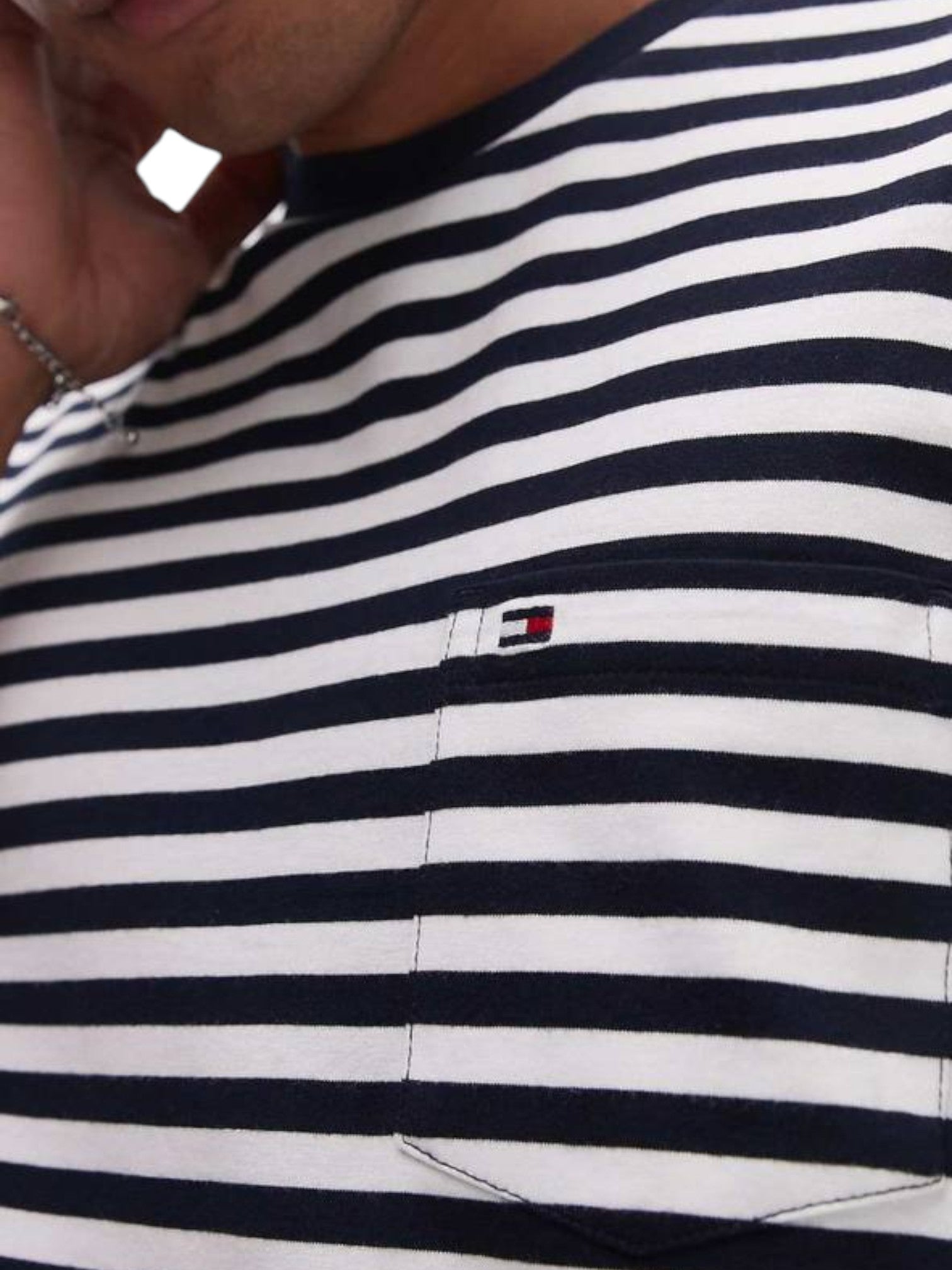 Close-up of a person wearing a navy and white striped shirt with a small logo on the chest. Tommy, Monza Outlet, Monza Fashion, Shein Outlet  