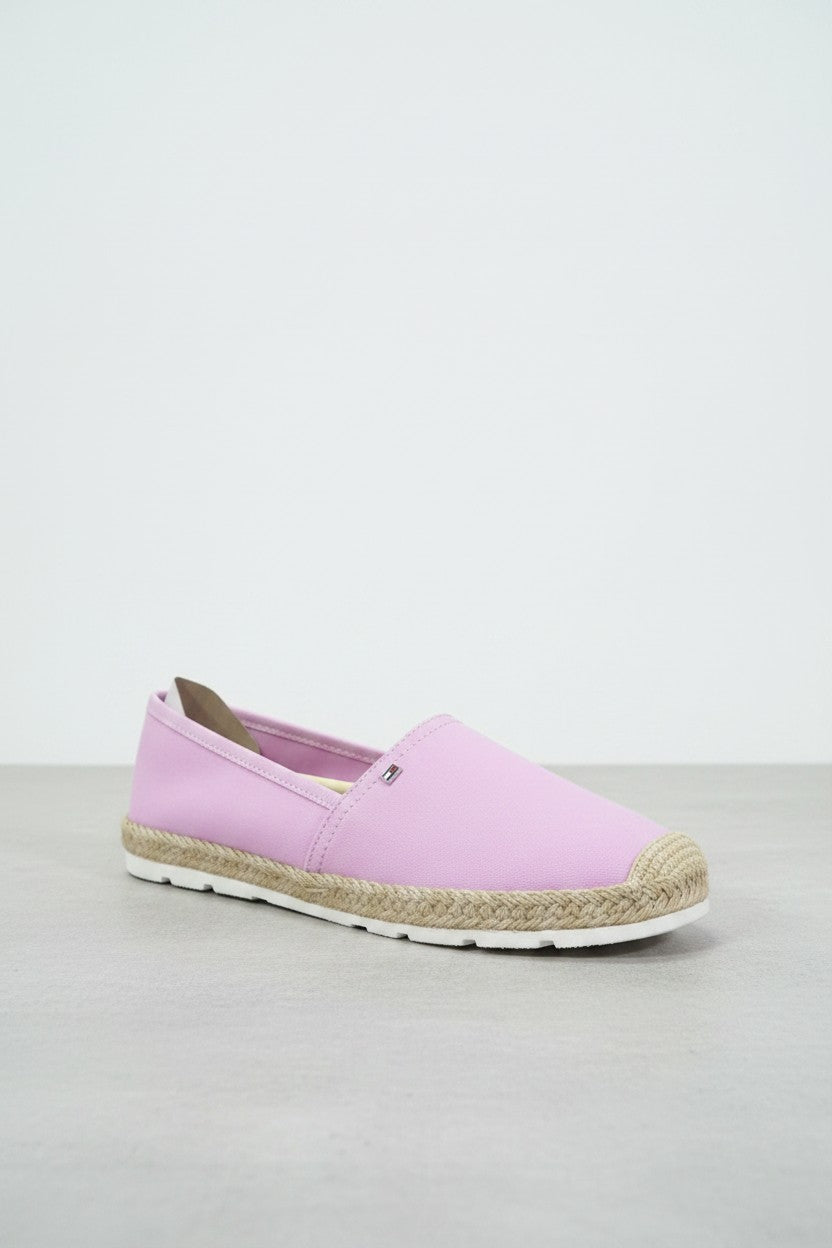 A light pink slip on espadrille shoe with a braided jute midsole and a white outsole, shown on a neutral gray studio background. Tommy Hilfiger, Monza Outlet, Monza Fashion, Shein Outlet
