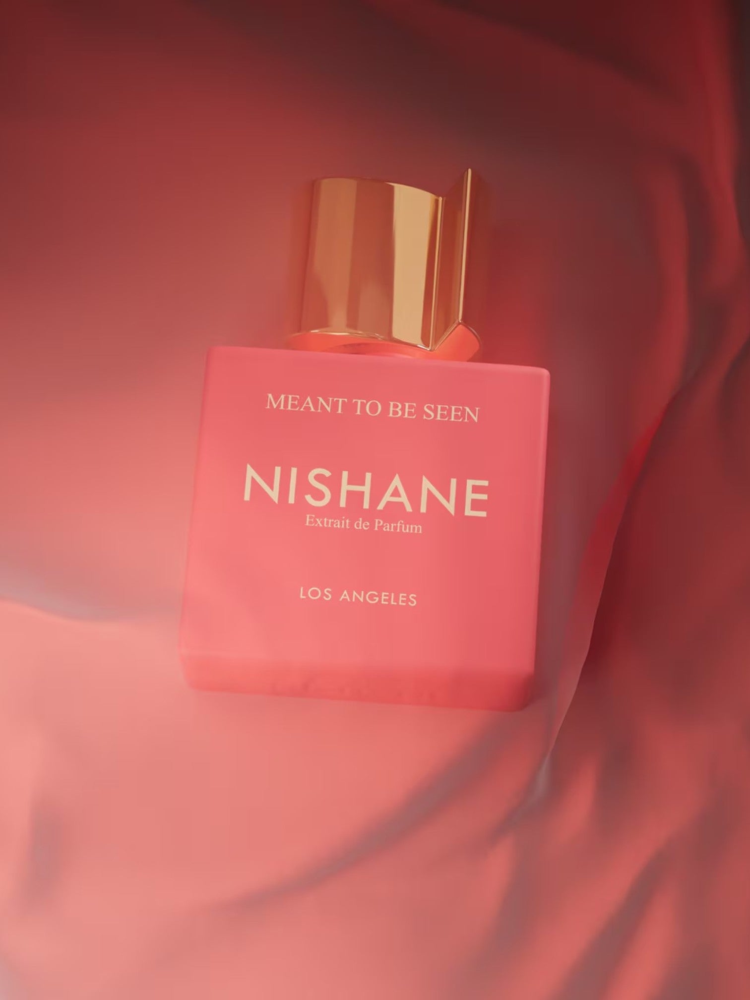Nishane perfume bottle with gold cap on a red fabric background. Nishane, Monza Outlet, Monza Fashion, Shein Outlet
