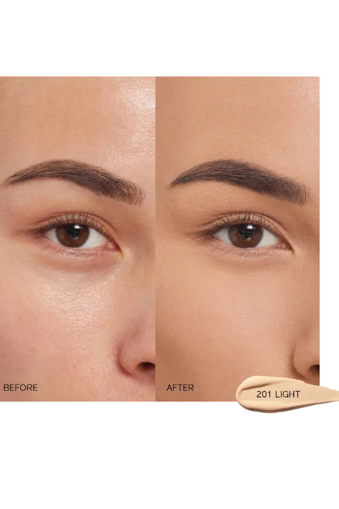 Before and after comparison of a woman's eye with concealer application, showing a beige color swatch labeled 201 Light. Shiseido, Monza Outlet, Monza Fashion, Shein Outlet