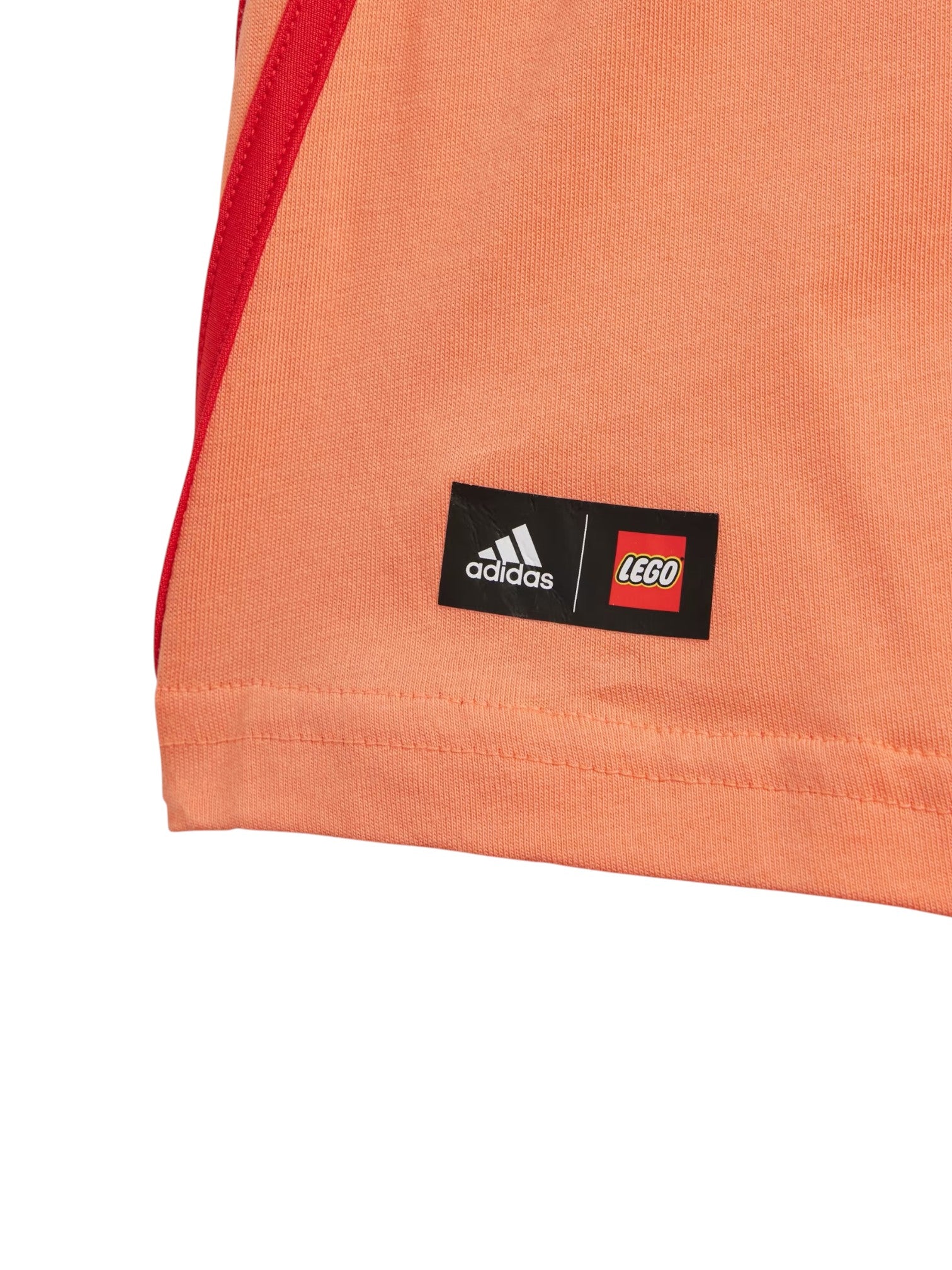 Close-up of an orange garment with Adidas and LEGO logos. Adidas, Monza Outlet, Monza Fashion, Shein Outlet