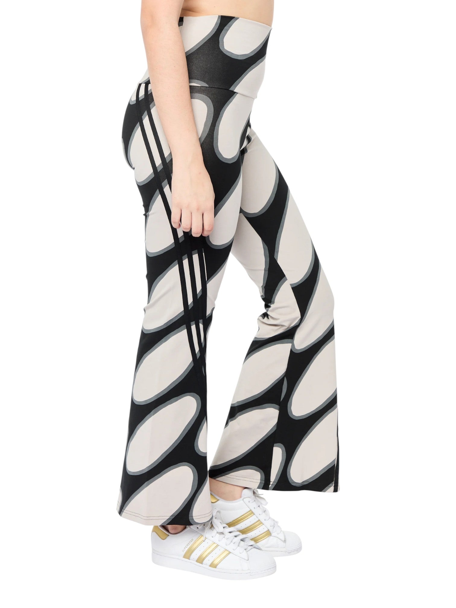 Person wearing black and white patterned pants with white sneakers on a white background. Adidas, Monza Outlet, Monza Fashion, Shein Outlet