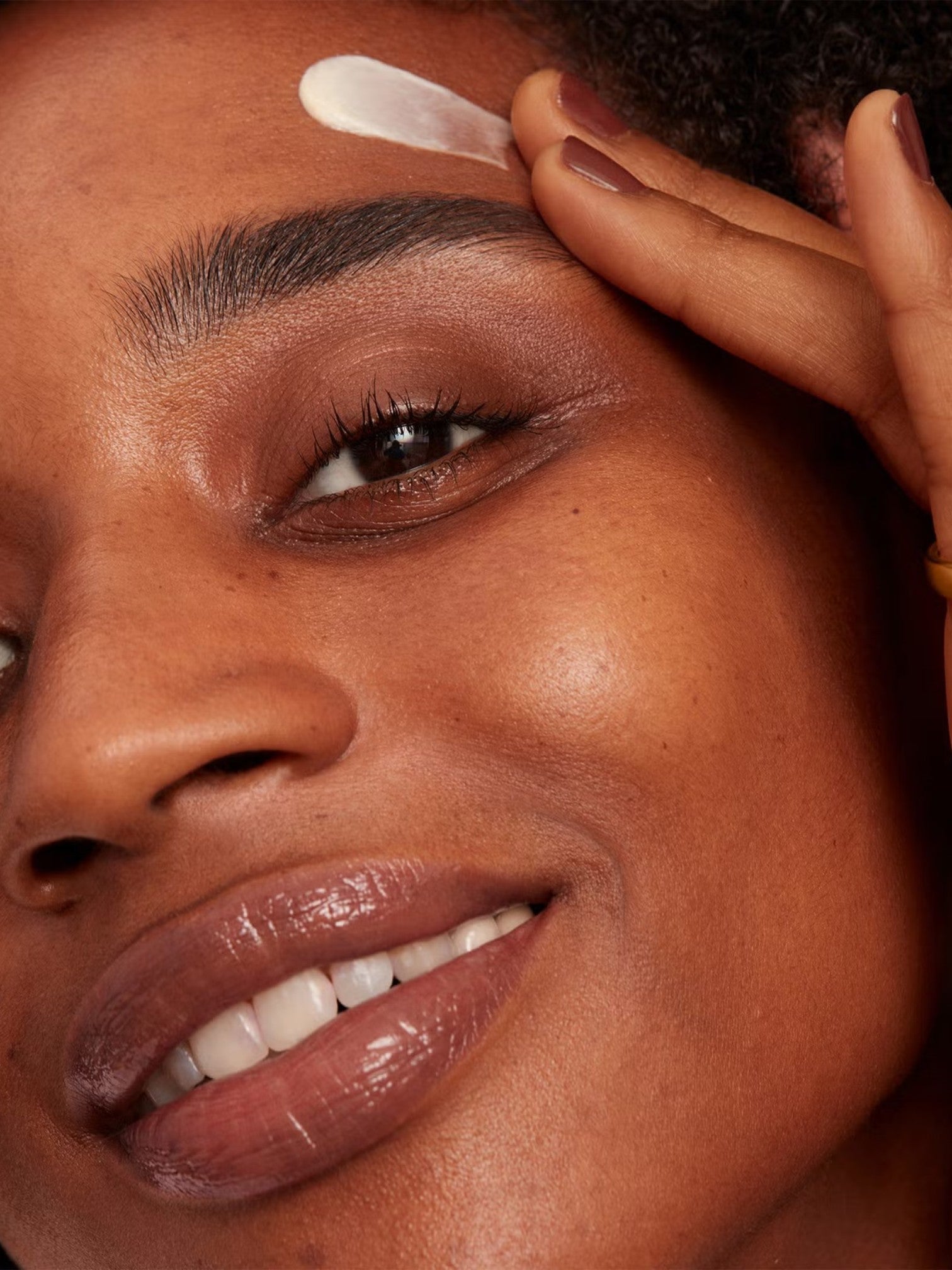 Close-up of a person applying a skincare product to their face. Bobbi Brown, Monza Outlet, Monza Fashion, Shein Outlet
