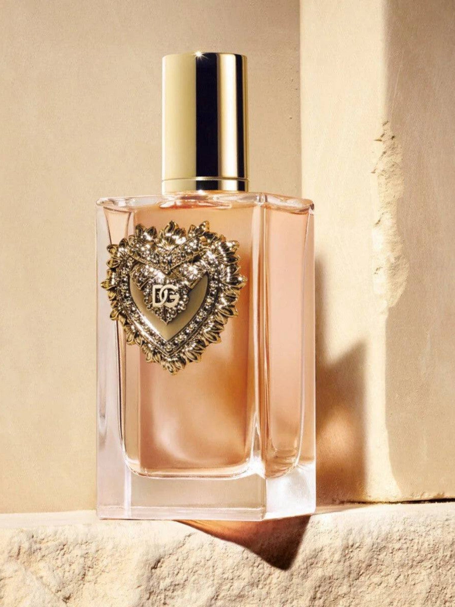 Perfume bottle with decorative heart-shaped cap on a beige background. Dolce & Gabbana, Monza Outlet, Monza Fashion, Shein Outlet