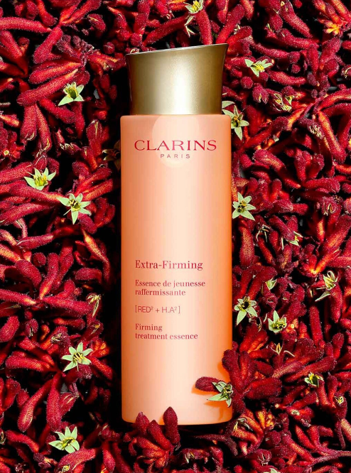 Clarins Extra-Firming treatment essence bottle on a red floral background. Clarins, Monza Outlet, Monza Fashion, Shein Outlet