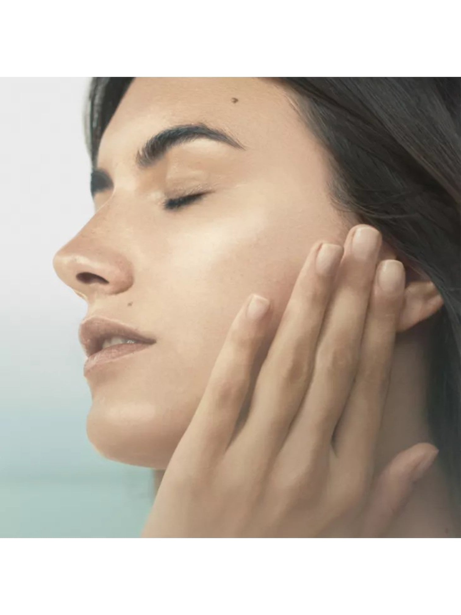 Close-up of a woman's face with her hand near her ear against a light background. Lamer, Monza Outlet, Monza Fashion, Shein Outlet