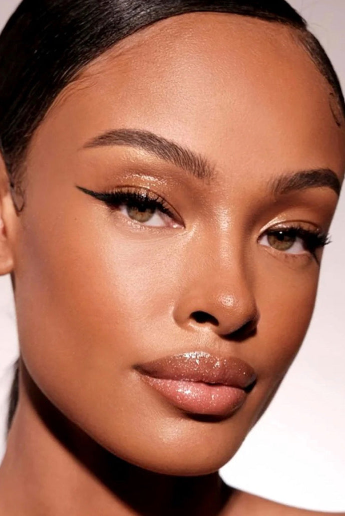 A close-up image of a person with a radiant complexion, featuring a subtle bronze contour on the cheeks, nose, and jawline. Monza Outlet