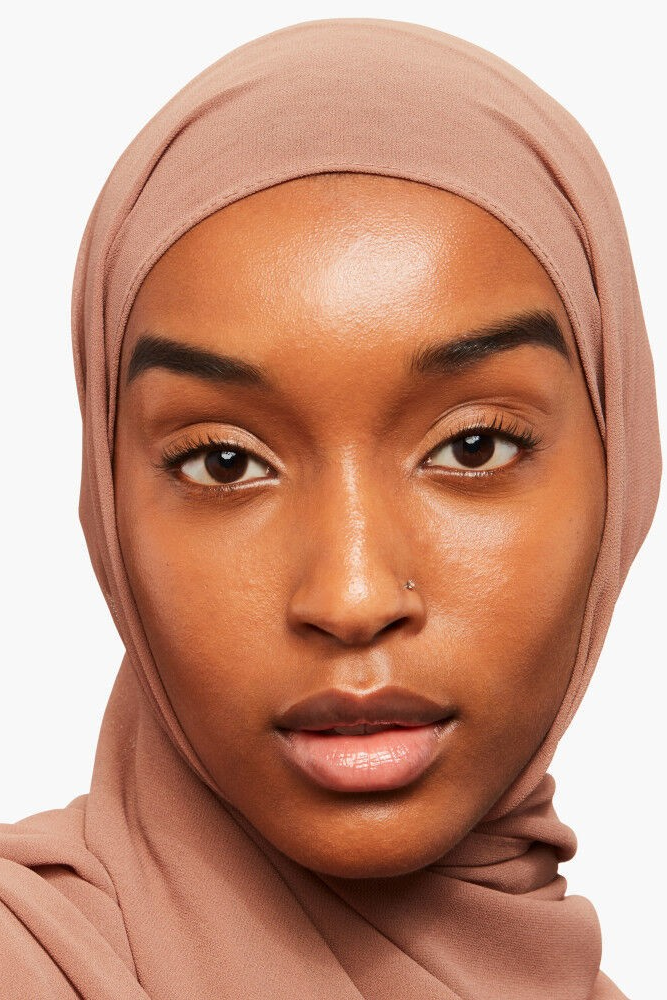 Woman wearing a beige hijab against a white background Monza fashion outlet, monza outlet, shein outlet, shien outlet cosmetics, makeup, perfume