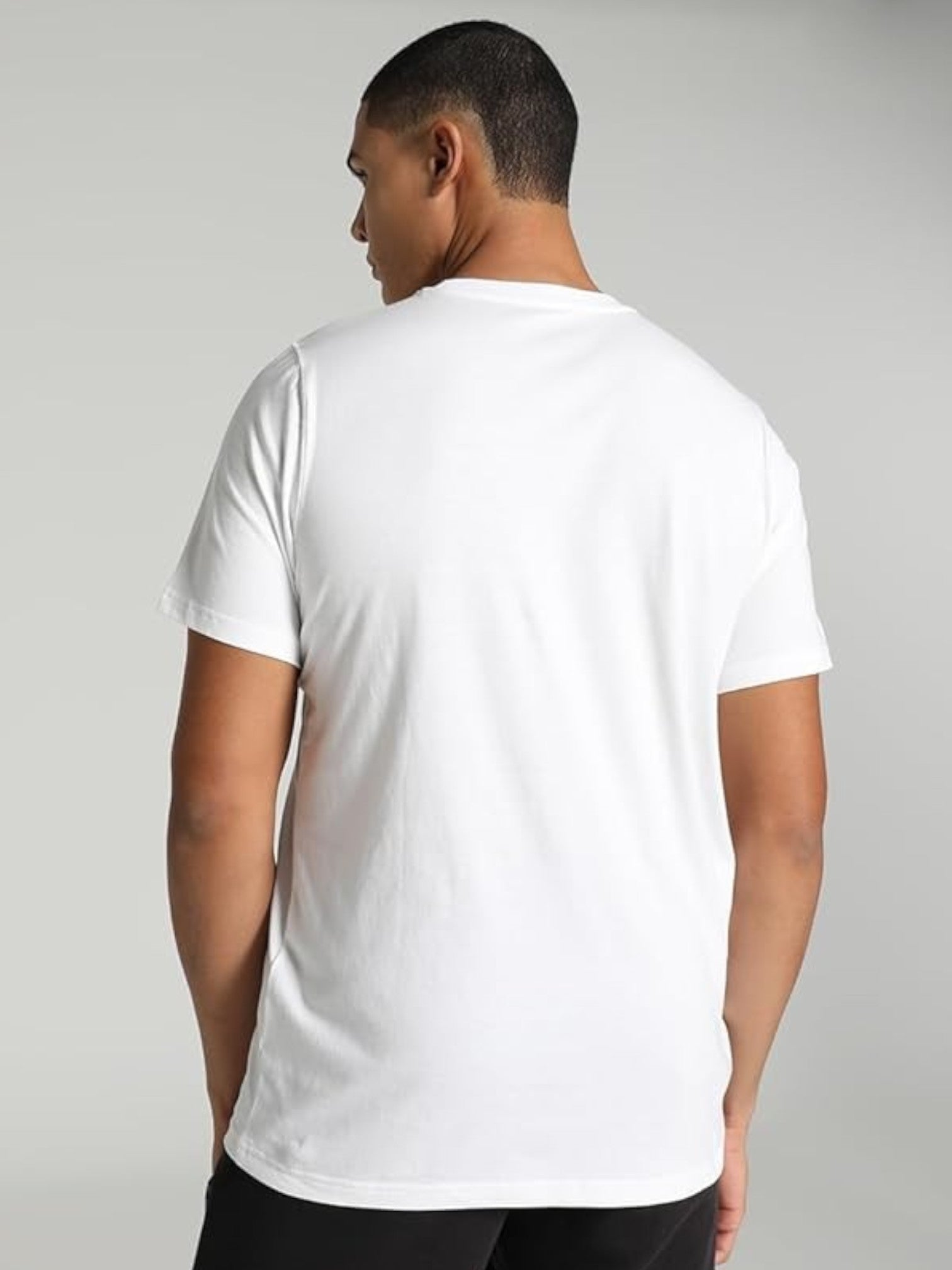 Person wearing a plain white t-shirt against a gray background.  Puma, Monza Outlet, Monza Fashion, Shein Outlet 