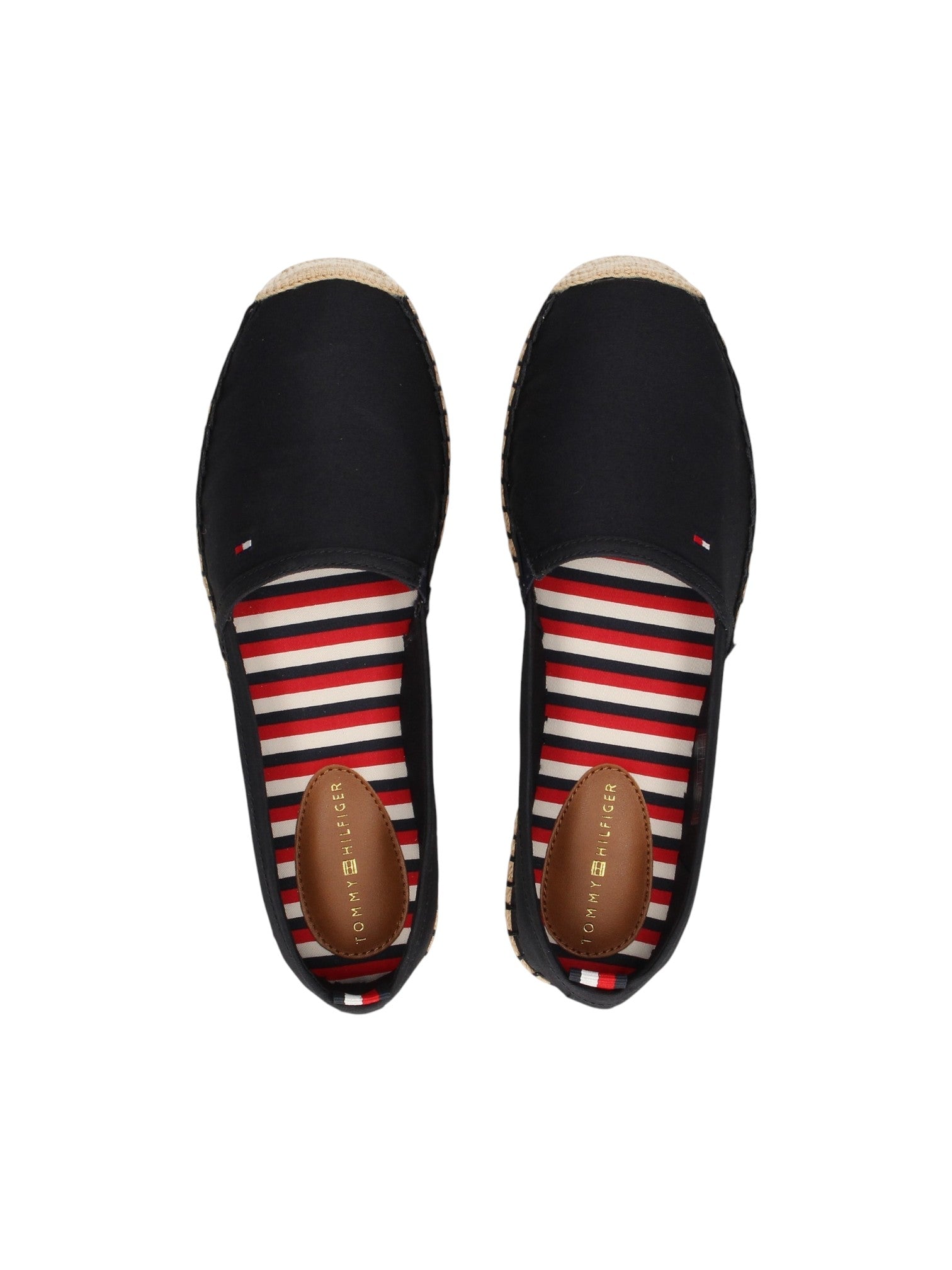 A pair of Tommy Hilfiger slip on espadrilles shown from a top down view. The shoes feature a navy blue canvas upper, a red, white, and navy striped insole, and a natural jute toe cap with a brown leather heel. Tommy Hilfiger, Monza Outlet, Monza Fashion, Shein Outlet