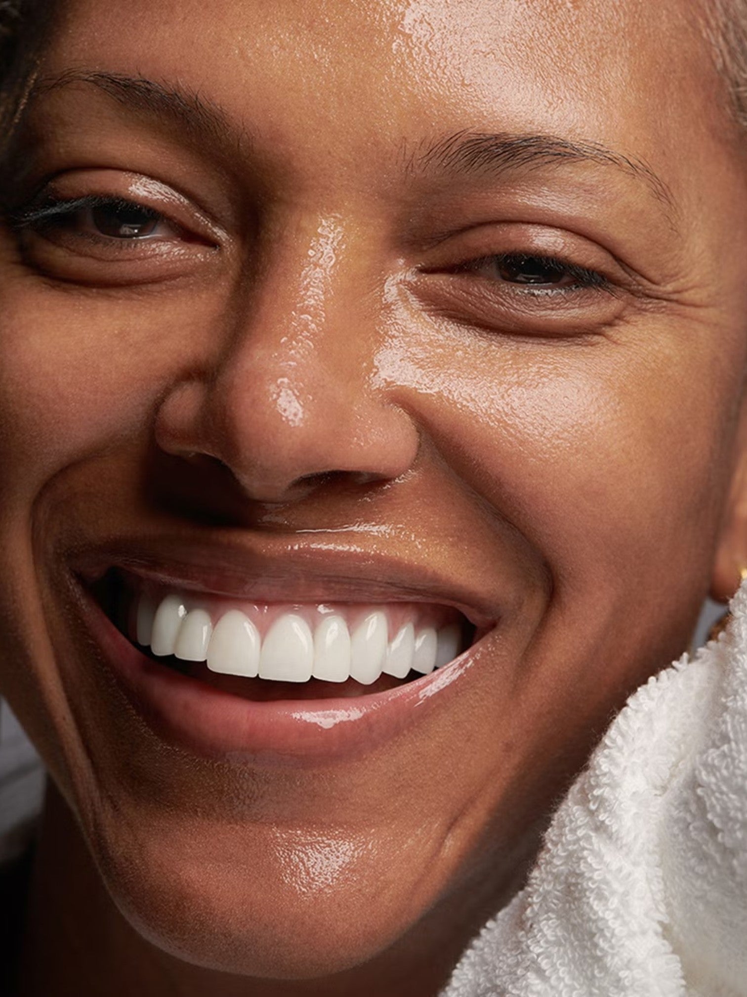 Close-up of a person with a bright smile, wearing a white towel. Bobbi Brown, Monza Outlet, Monza Fashion, Shein Outlet