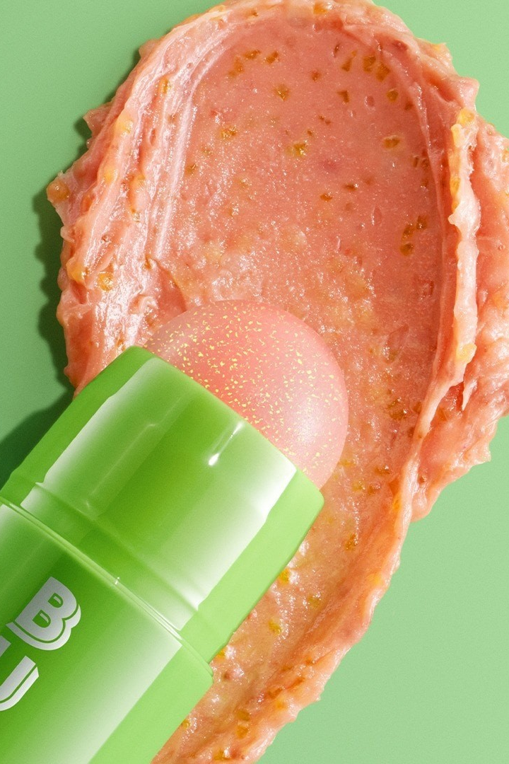 Green lip balm with pink substance on a green background Monza fashion outlet, monza outlet, shein outlet, shien outlet cosmetics, makeup, perfume