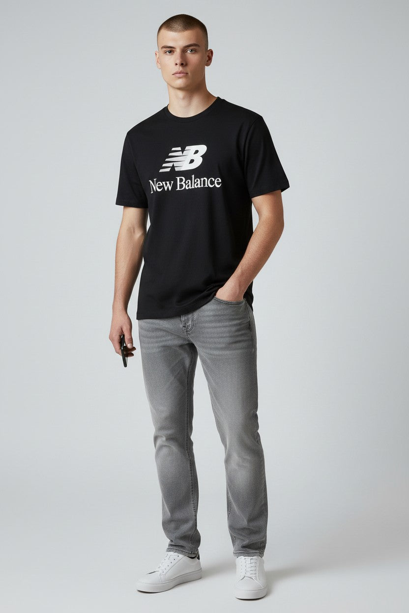 Man wearing a black New Balance t-shirt and gray jeans on a white background. New Balance, Monza Outlet, Monza Fashion, Shein Outlet