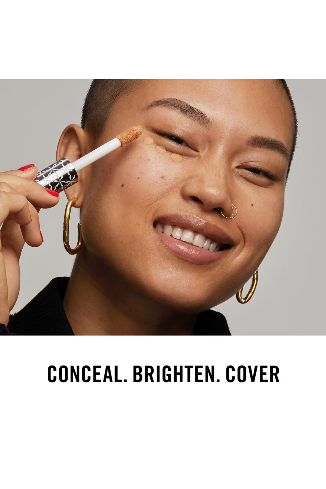 Person applying concealer with a brush to their face, wearing gold hoop earrings. Monza fashion outlet, monza outlet, shein outlet, shien outlet cosmetics, makeup, perfume