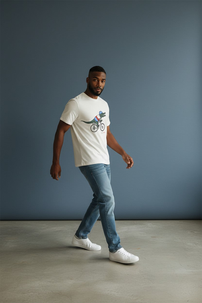 Man wearing a white t-shirt with a graphic design, blue jeans, and white sneakers against a gray background. Lacoste, Monza Outlet, Monza Fashion, Shein Outlet