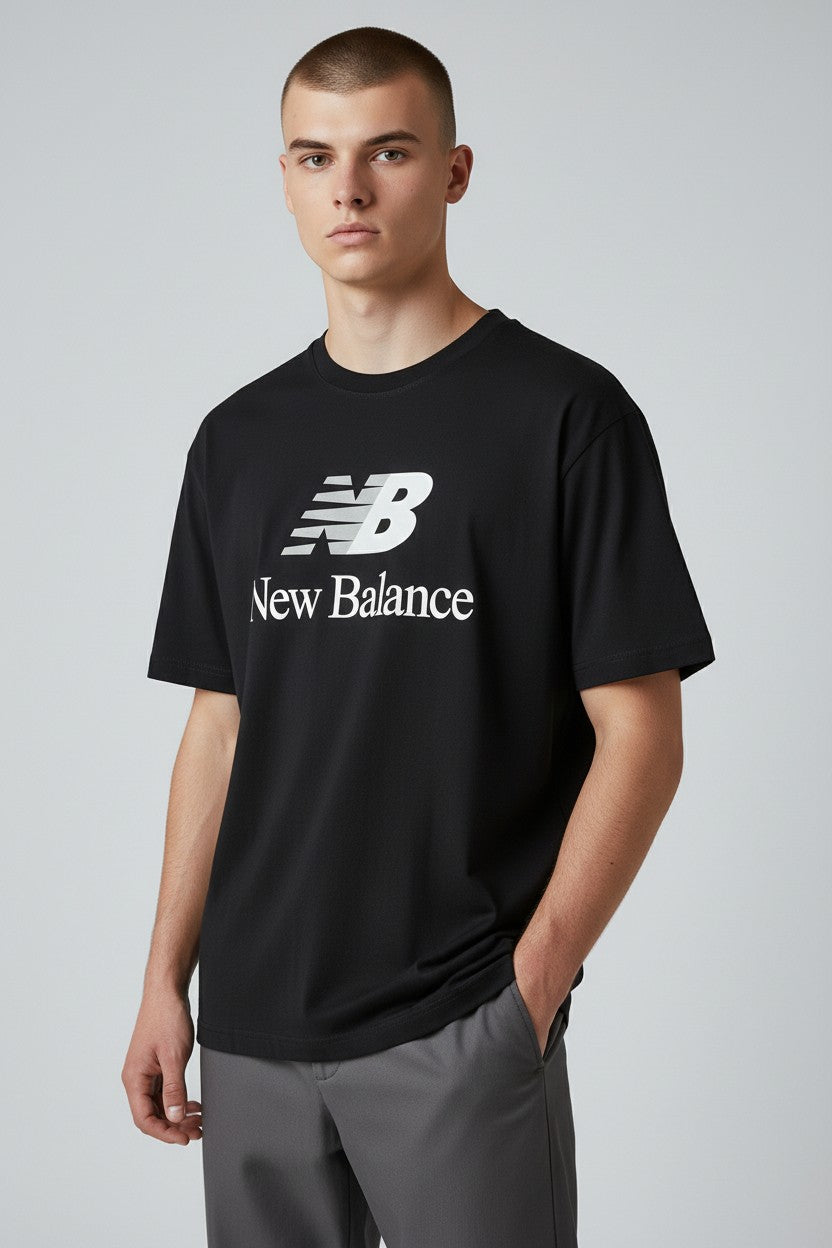 Person wearing a black New Balance t-shirt on a gray background. New Balance, Monza Outlet, Monza Fashion, Shein Outlet