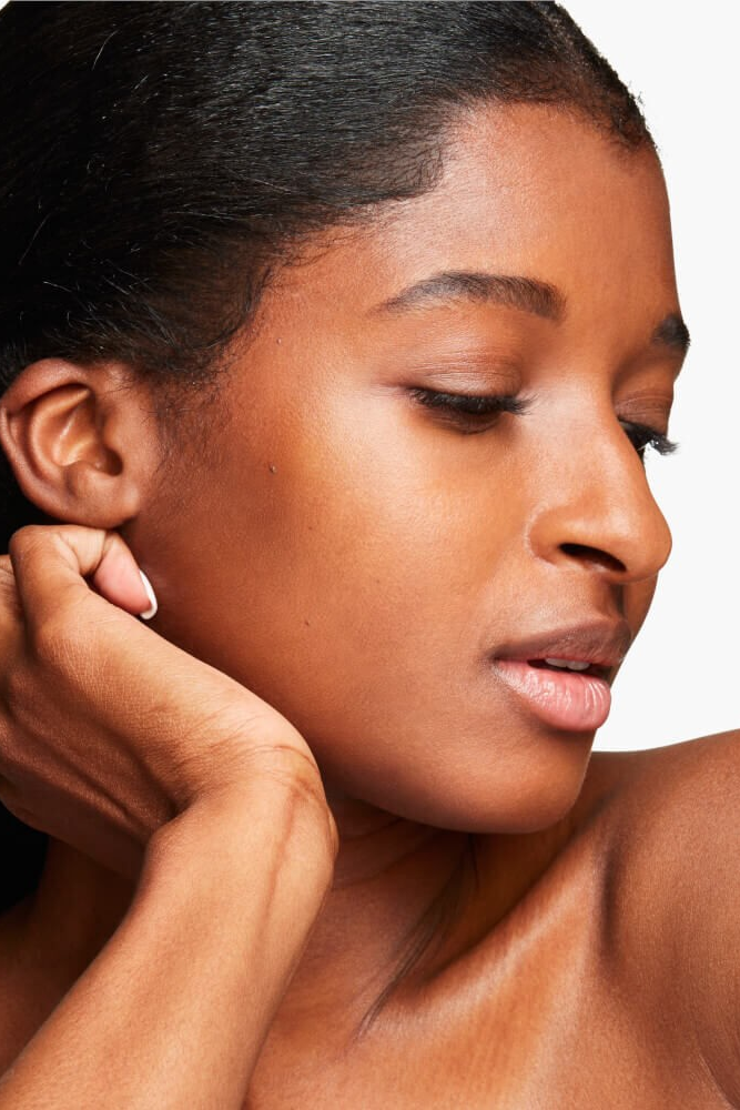 Woman adjusting an earring against a neutral background Monza fashion outlet, monza outlet, shein outlet, shien outlet cosmetics, makeup, perfume