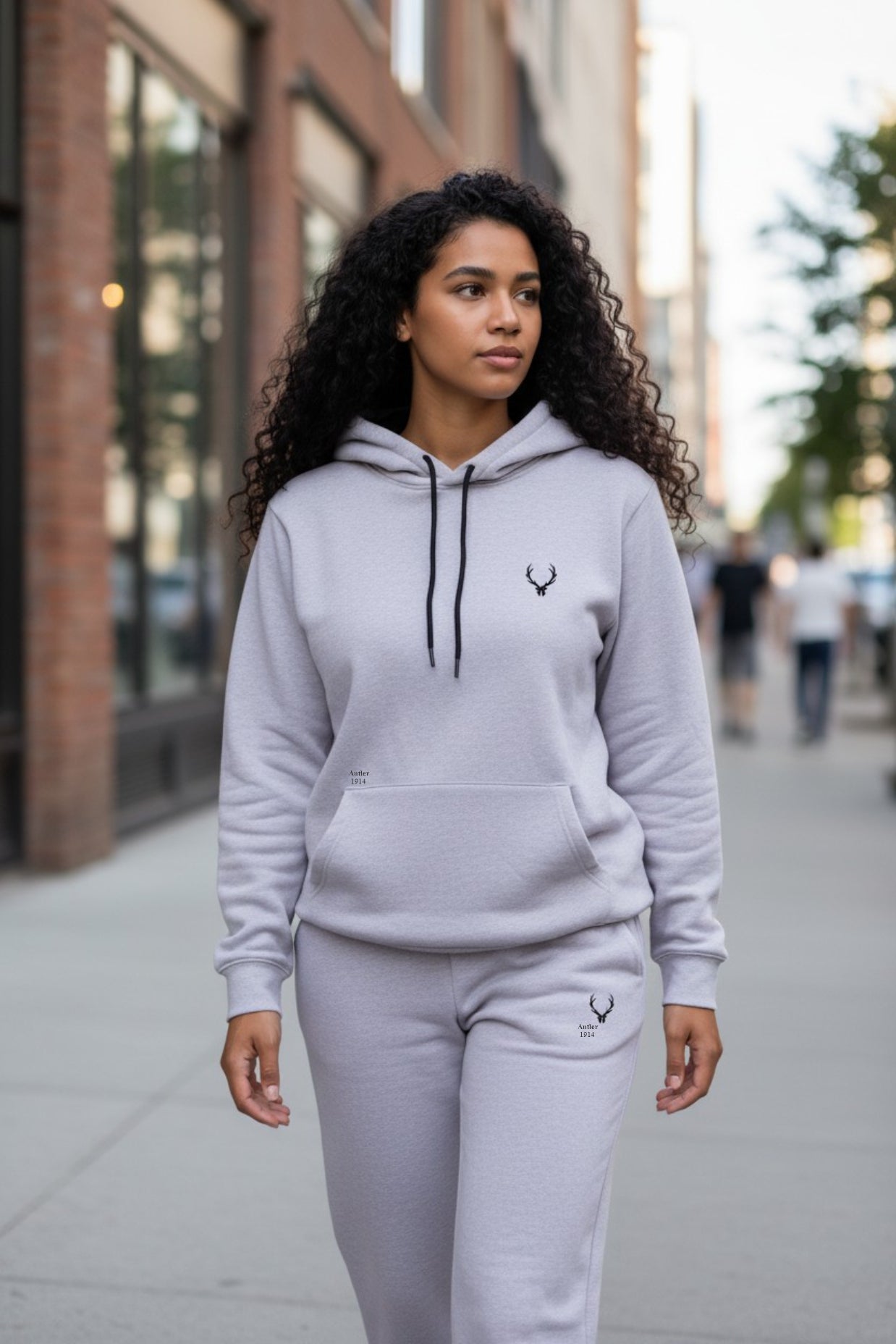 Woman wearing a gray hoodie and pants with a brand logo on a city street. Antler, Monza Outlet, Monza Fashion, Shein Outlet