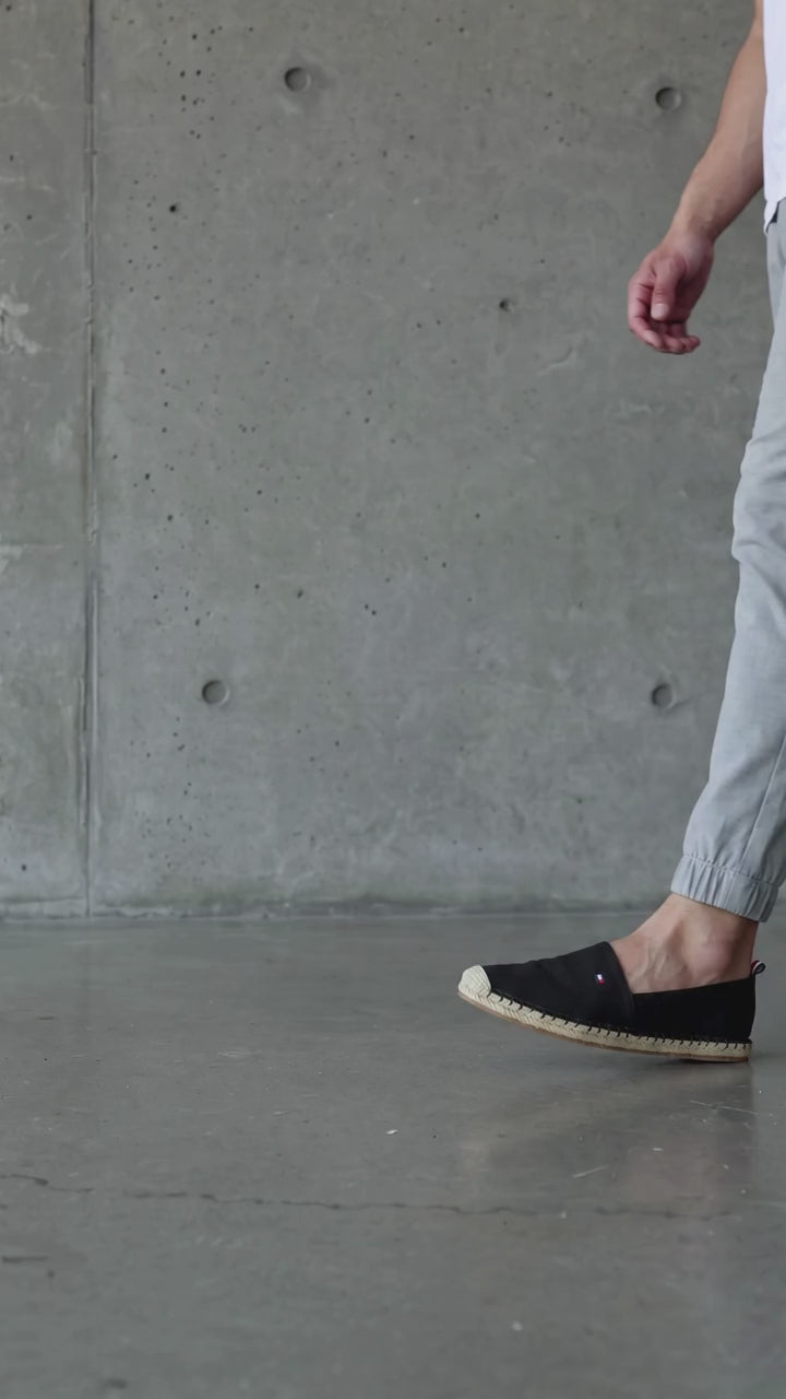A single black slip on espadrille shoe shown from a top down view, featuring a red, white, and blue striped insole and a tan footbed. Tommy Hilfiger, Monza Outlet, Monza Fashion, Shein Outlet